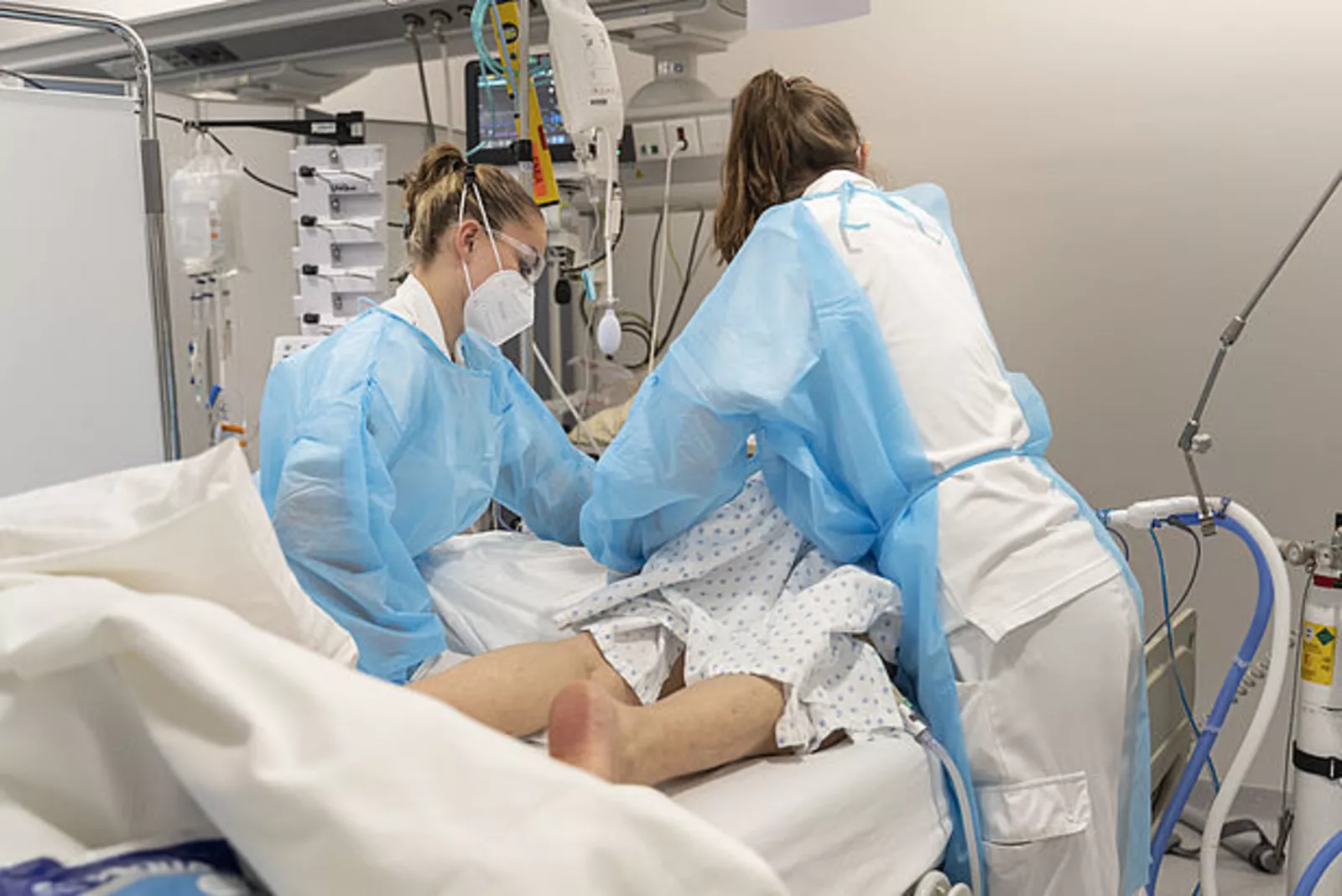 Photo de deux soignantes au chevet d'un patient dans un lit